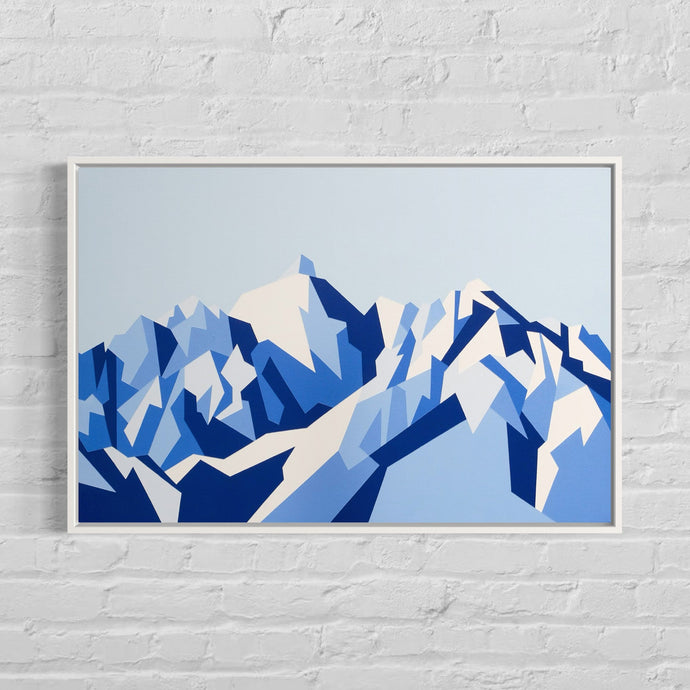 Framed abstract mountain painting hung on a white brick wall